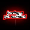 Neon sign with colorful letters spelling out 'Your Name Moment' in a red, RGB glow.