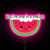 Neon pink melon sign with RGB lighting effects, a colorful food display at an outdoor market or fair.